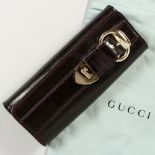 A GUCCI BLACK PATENT BAG, in a Gucci bag.