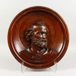 A CIRCULAR OAK PANEL, carved with a male bust. 16ins diameter.