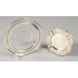 AN ETCHED GLASS CIRCULAR DISH, with silver border, 6ins diameter, and an engine turned ashtray,