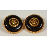 A PAIR OF BLACK AND GILT CIRCULAR EAR CLIPS, with cloverleaf decoration. 4cms diameter.