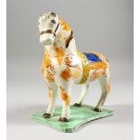 A STAFFORDSHIRE COLOURED SPONGE WARE HORSE on a shaped base. 6ins long.