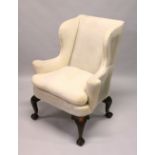 A GEORGE III DESIGN WALNUT WING ARMCHAIR, with carved cabriole legs all round and claw and ball