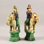 A PAIR OF POLYCHROME DECORATED POTTERY MODELS OF ELEPHANTS AND RIDERS. 12ins high.