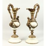 A PAIR OF 20TH CENTURY BRONZE AND PORCELAIN CLASSICAL EWERS, with dolphin handles and cherub mounts.