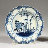 A SMALL 18TH CENTURY LIVERPOOL SCALLOPED PLATE, painted with bamboo and flowering plants.