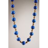 A STRING OF NINETEEN SIMULATED LAPIS BEADS.