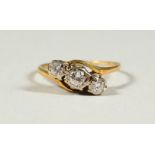 AN 18CT GOLD THREE STONE DIAMOND CROSSOVER RING.