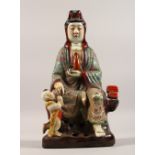 A PORCELAIN FIGURE OF GUANYIN, seated with a child at her feet. 11.5ins high.