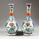 A GOOD PAIR OF IZNIK POTTERY WATER BOTTLES, enamel decorated with flowers. 12ins high.