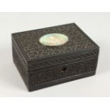 A GOOD 19TH CENTURY INDIAN CARVED EBONY CASKET, the top inlaid with a painted oval panel depicting