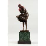 AN ART DECO STYLE BRONZE FEMALE FIGURE, her hands wrapped up in a scarf, on a square marble base.