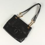 A BLACK LEATHER HANDBAG, with large embossed Chanel logo, leather handle, in a travelling bag. 32cms