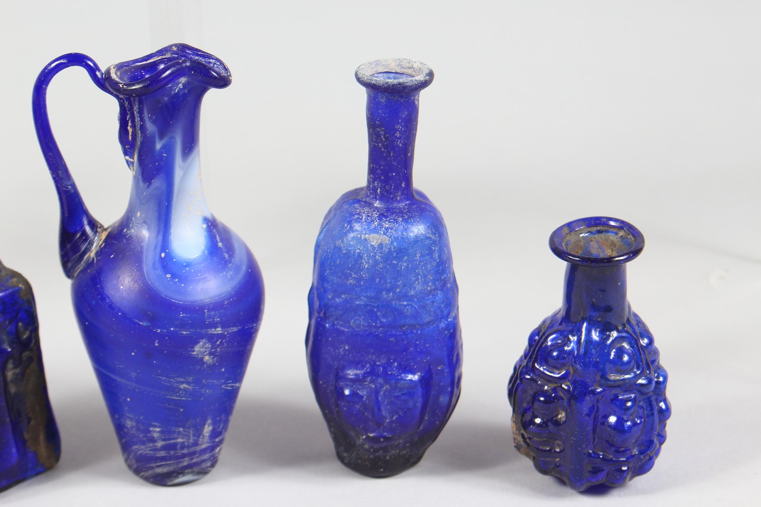 A COLLECTION OF ROMAN GLASS BOTTLES, some with moulded decoration as heads, bunches of grapes (10). - Image 4 of 10