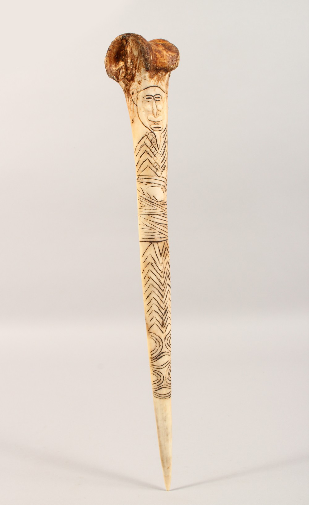 A CARVED BONE DAGGER, with incised decoration. 15.75ins long.