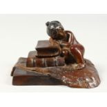 A SMALL CAST BRONZE MODEL OF A YOUNG GIRL ASLEEP AGAINST A PILE OF BOOKS. 5ins wide.