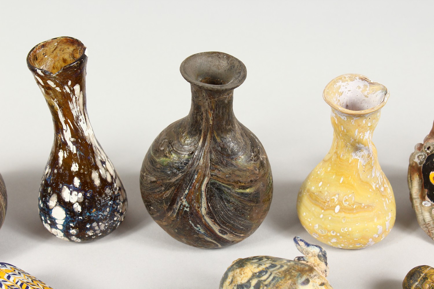 A GROUP OF THIRTEEN ROMAN GLASS BOTTLES AND JARS, including three tops in the form of heads (13). - Image 3 of 11