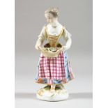 A SMALL MEISSEN FIGURE OF A GIRL, holding a basket of flowers in both hands. 5.25ins high.
