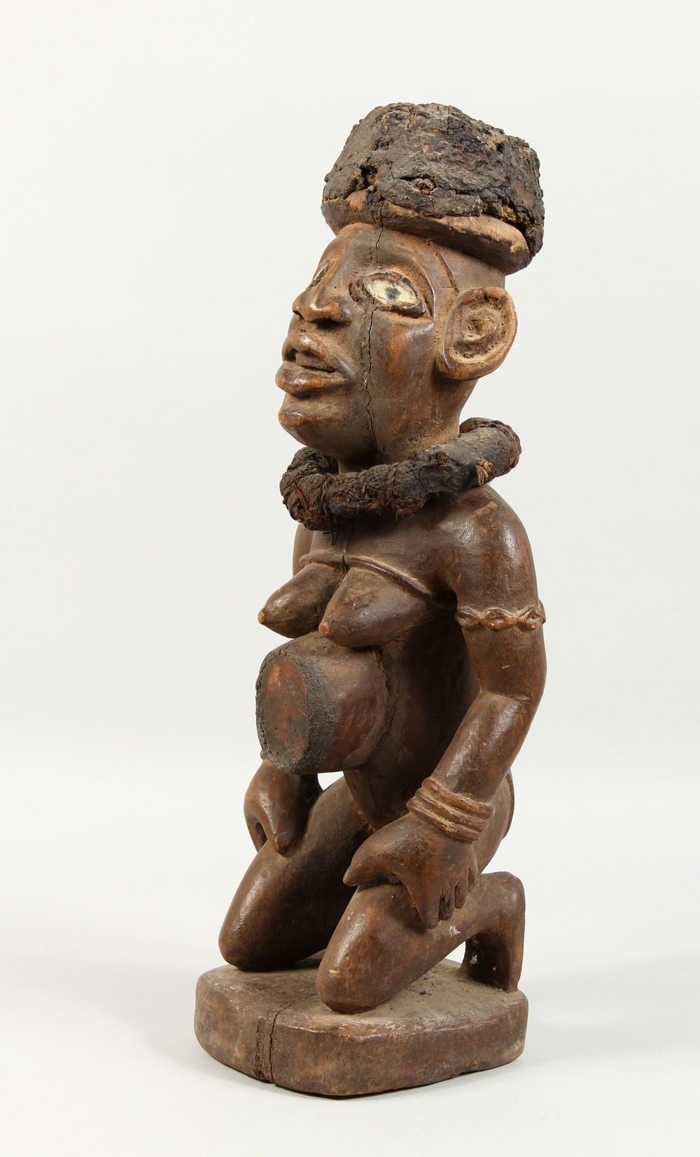 A CARVED WOOD AFRICAN FIGURE, a kneeling female nude wearing a large collar. 20ins high.