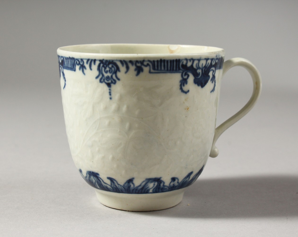 A WORCESTER BLUE AND WHITE FLORAL MOULDED COFFEE CUP, painted with two elaborate borders, crescent