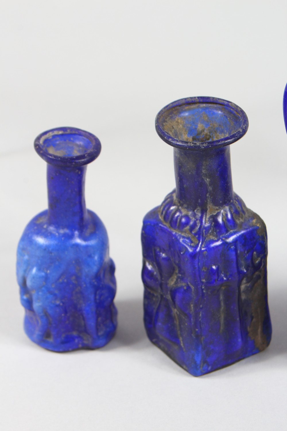 A COLLECTION OF ROMAN GLASS BOTTLES, some with moulded decoration as heads, bunches of grapes (10). - Image 5 of 10