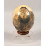 AN OSTRICH EGG, decorated with lions and leopards, on a Perspex stand. 8.5ins high.
