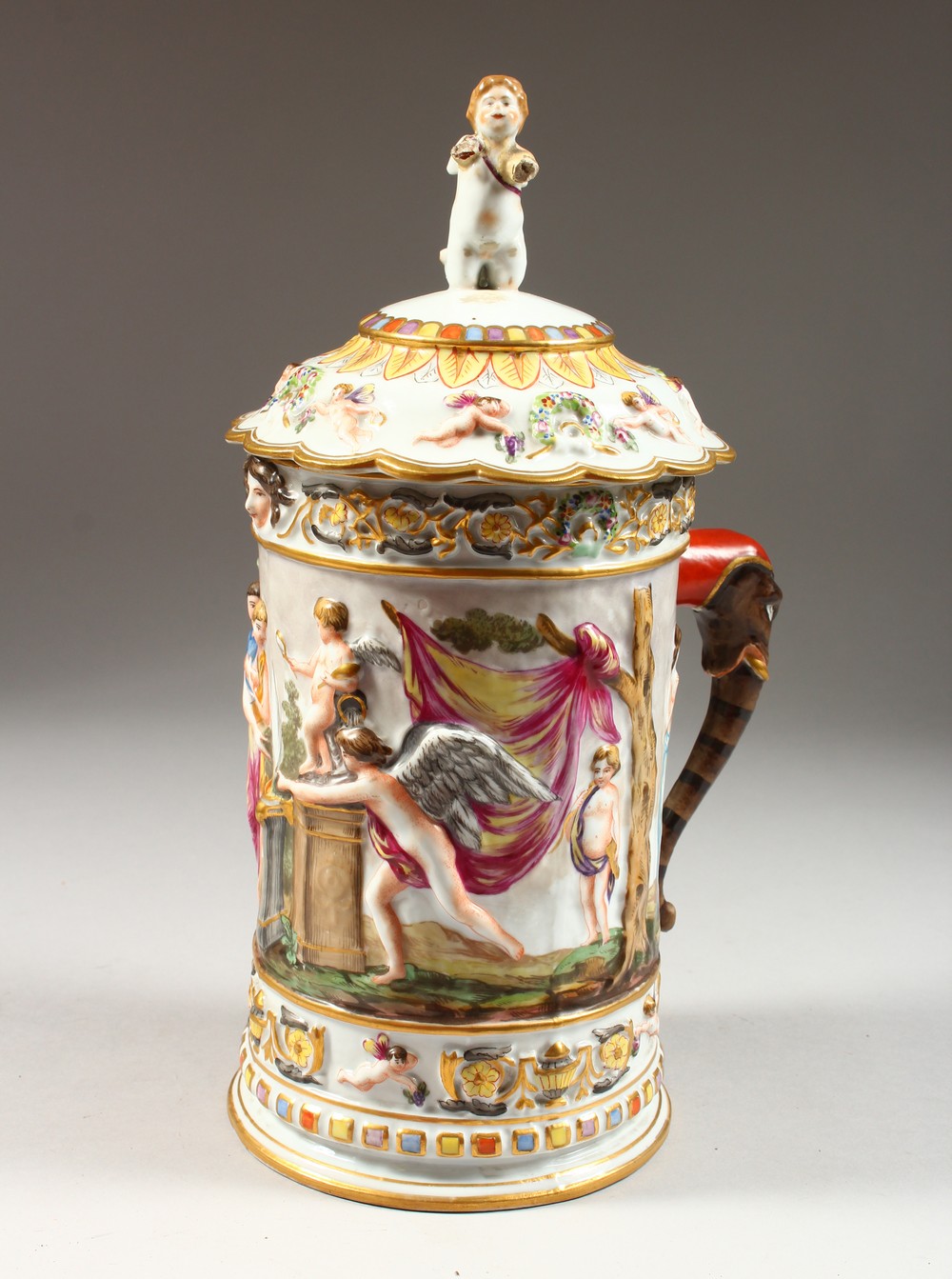 A LARGE CAPODIMONTE TANKARD AND COVER, with classical figures in relief. Mark in blue. 12.5ins