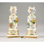 A PAIR OF SMALL MEISSEN CANDLESTICKS, with floral encrusted decoration, on square bases, crossed