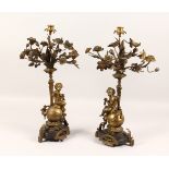 A PAIR OF 19TH CENTURY BRONZE NATURALISTIC CANDELABRA with cherub supports. 21ins high.