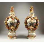 A PAIR OF MEISSEN STYLE VASES, COVERS AND STANDS, with cherubs, floral garlands and panels decorated