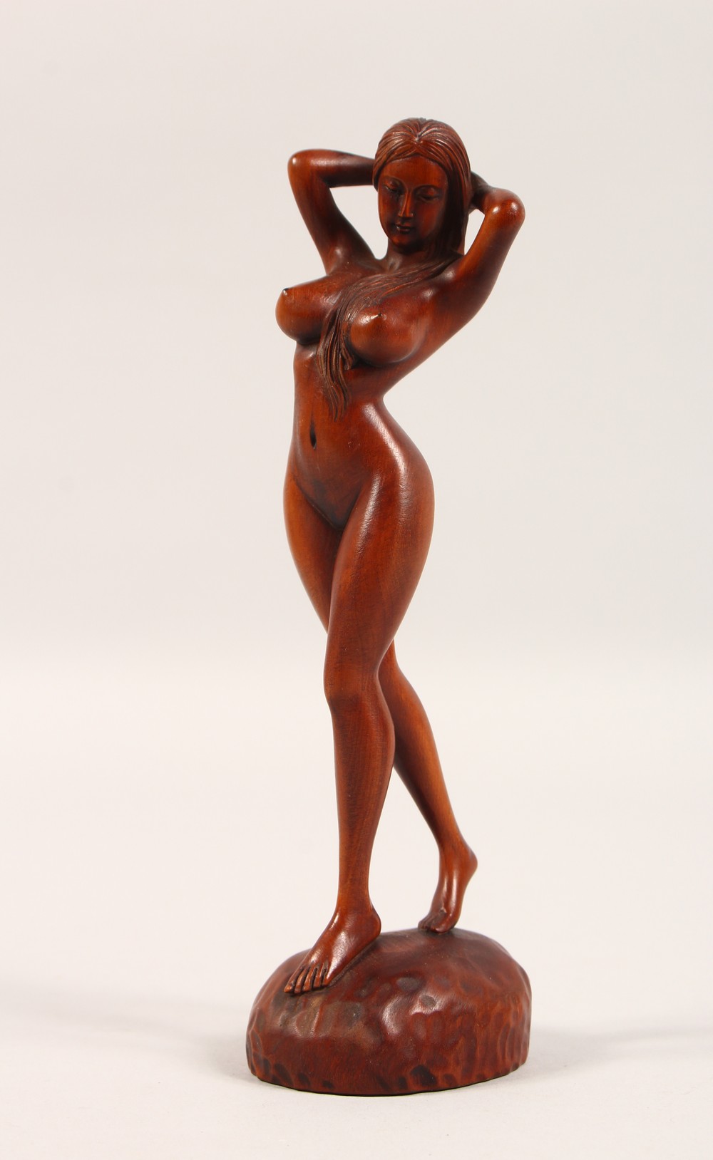 A SMALL CARVED WOOD FIGURE, standing female nude. 7ins high.