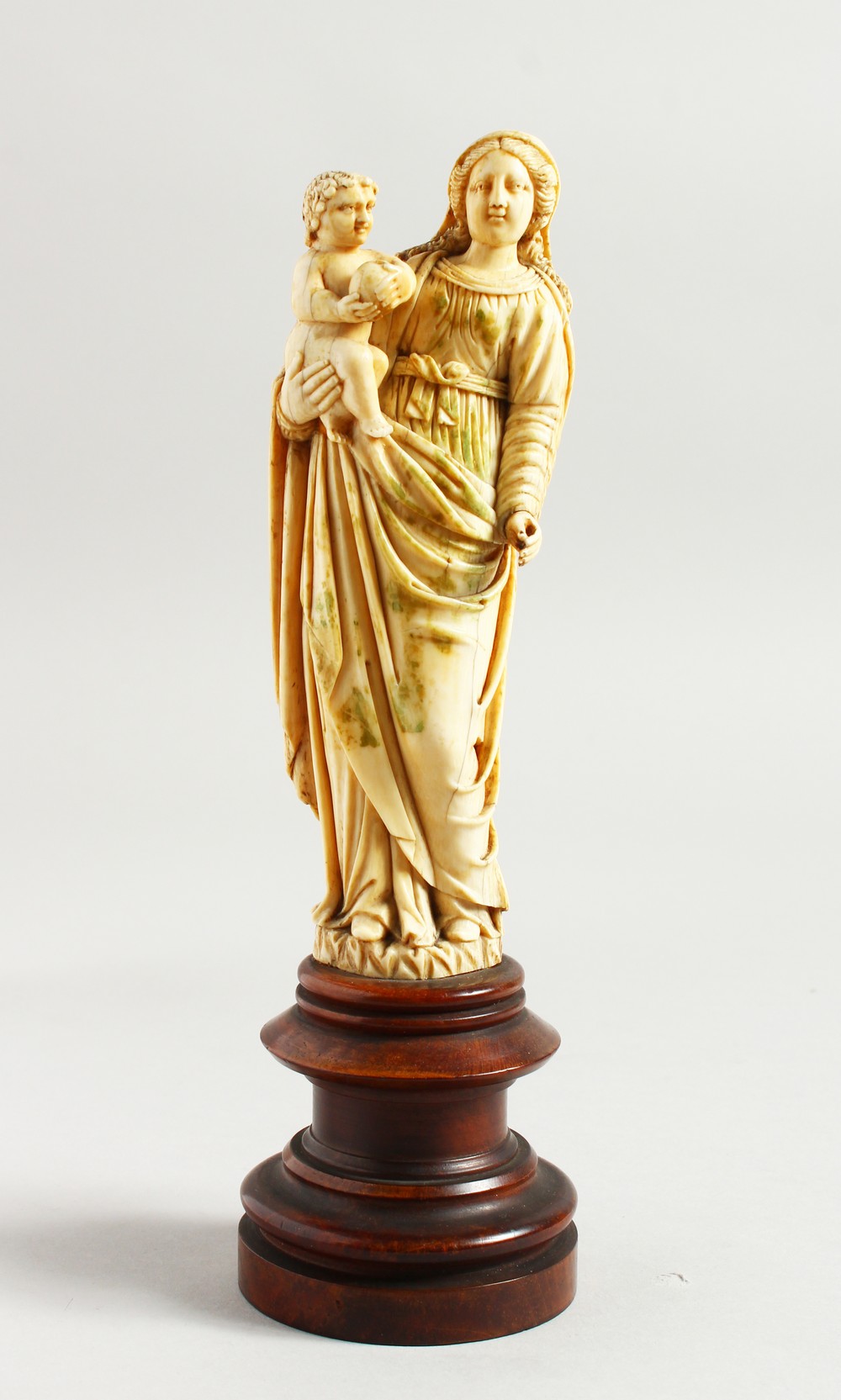 A GOOD 17TH-18TH CENTURY GOAN CARVED IVORY MADONNA AND CHILD on a circular wooden base. 6.25ins