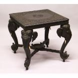 AN EARLY 20TH CENTURY CEYLONESE CARVED EBONY LOW TABLE, with an elephant head leg to each corner.