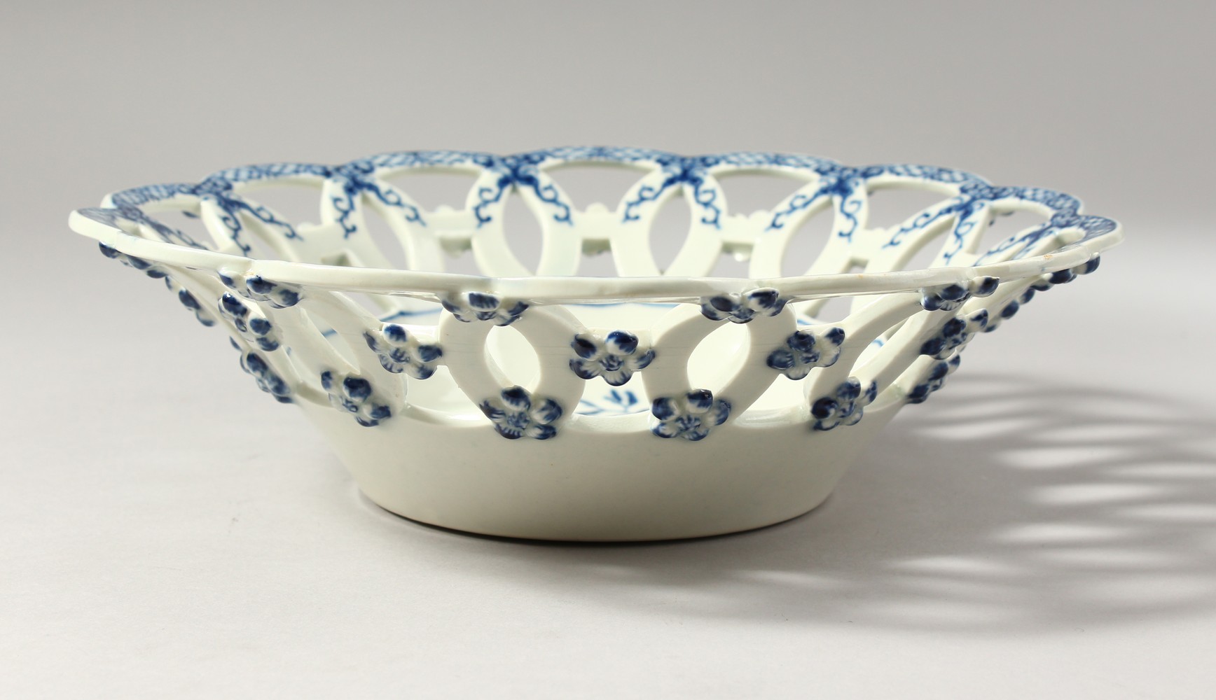 A WORCESTER BLUE AND WHITE OPEN WORK BASKET, decorated with fir cones and an elaborate border,