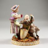A MEISSEN GROUP OF TWO CHILDREN, the seated boy holding a grape vine, the girl with a jug of wine