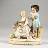 A MEISSEN GROUP OF TWO CHILDREN, the boy standing playing a pipe, the girl seated holding grapes,
