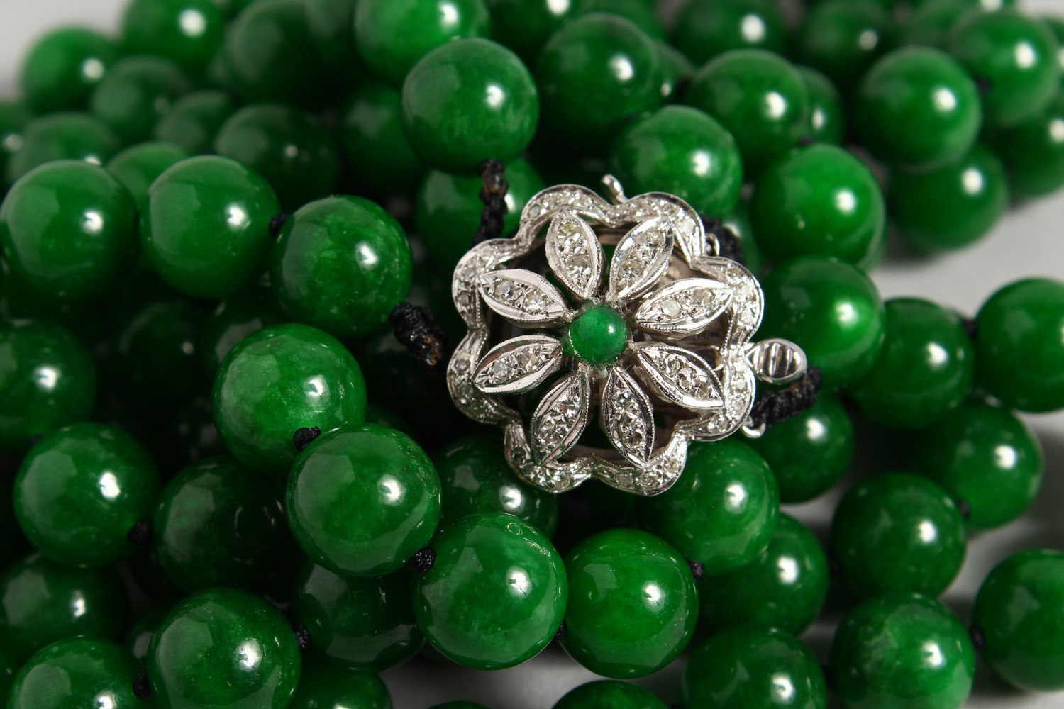 A GOOD DOUBLE ROW OF JADE BEADS, with 18ct white gold and diamond clasp. 25ins long.