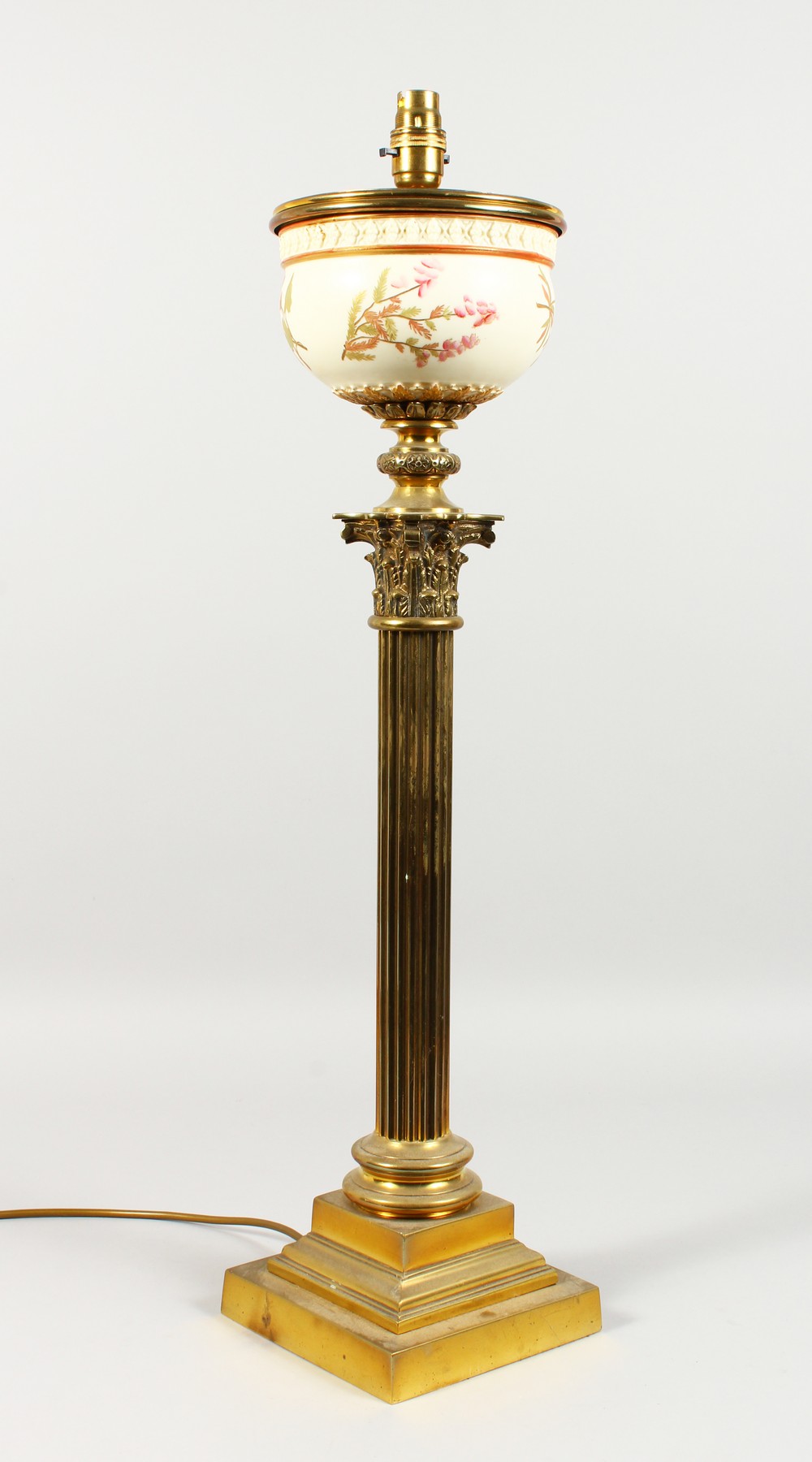 A GOOD BRASS CORINTHIAN COLUMN TABLE LAMP, possibly converted from an oil lamp, with Royal Worcester