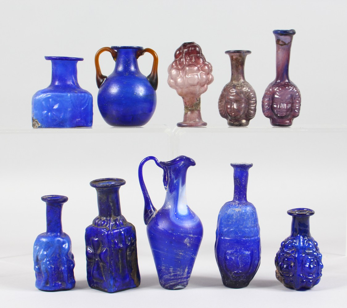 A COLLECTION OF ROMAN GLASS BOTTLES, some with moulded decoration as heads, bunches of grapes (10).