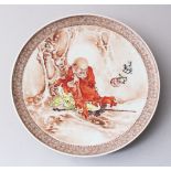 A CHINESE REPUBLICAN STYLE ENAMELLED PORCELAIN DISH, depicting scenes of a luohan resting under a