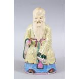 A 19TH CENTURY CHINESE FAMILLE ROSE PORCELAIN FIGURE OF SHOU LAO, in a seated pose holding a