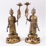 A GOOD PAIR OF 20TH CENTURY CHINESE BRONZE CANDLE STICKS, in the form of figures holding flowers,