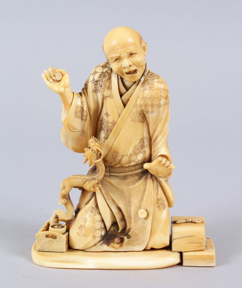 A JAPANESE MEIJI PERIOD CARVED IVORY OKIMONO OF AN ARHAT & DRAGON, the elder on his knees with his