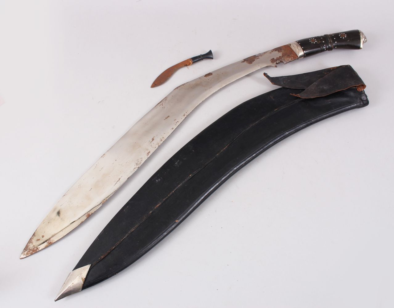 A LARGE NEPALESE KUKRI in a leather scabbard with small knife.