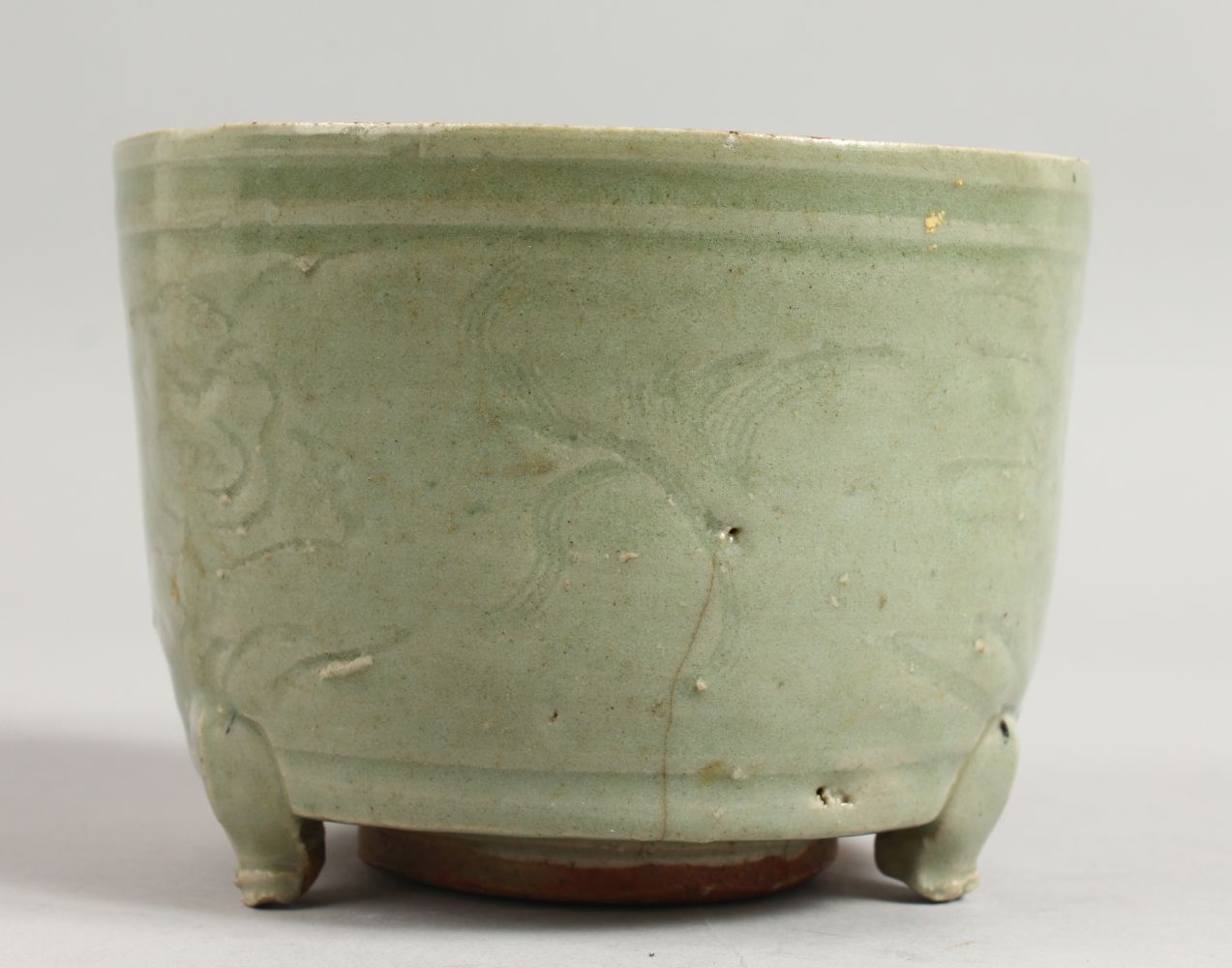 AN EARLY CHINESE LONGQUAN CELADON CIRCULAR CELADON CENSER on three legs. 5.5ins diameter.