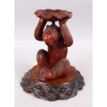A JAPANESE MEIJI PERIOD CARVED HARDWOOD STAND IN THE FORM OF A MONKEY, the monkey realistically