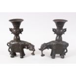 A GOOD PAIR OF 19TH CENTURY CHINESE BRONZE ELEPHANT CANDLESTICKS, the mirrored pair with miniature
