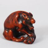 A JAPANESE LATE EDO PERIOD CARVED WOODEN NETSUKE OF A WOLF WITH A DEER HAUNCH, the wolf in a semi