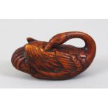 A JAPANESE EDO PERIOD CARVED WOODEN NETSUKE OF A CRANE, the crane in recumbent position with its
