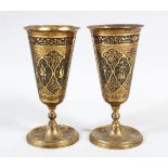 A PAIR OF ISLAMIC BRASS WINE GOBLETS, engraved with figures, 18.5cm high.
