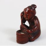 A JAPANESE MEIJI PERIOD CARVED WOODEN NESUKE, of a lady knelt beside her toilet, himotoshi formed